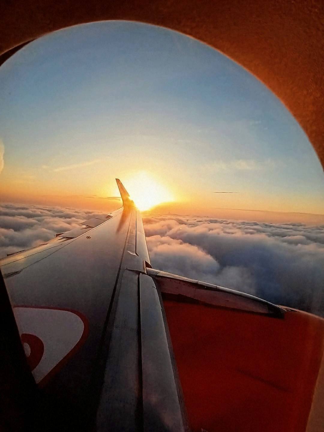View of an aeroplane wing and sunset through a passenger window