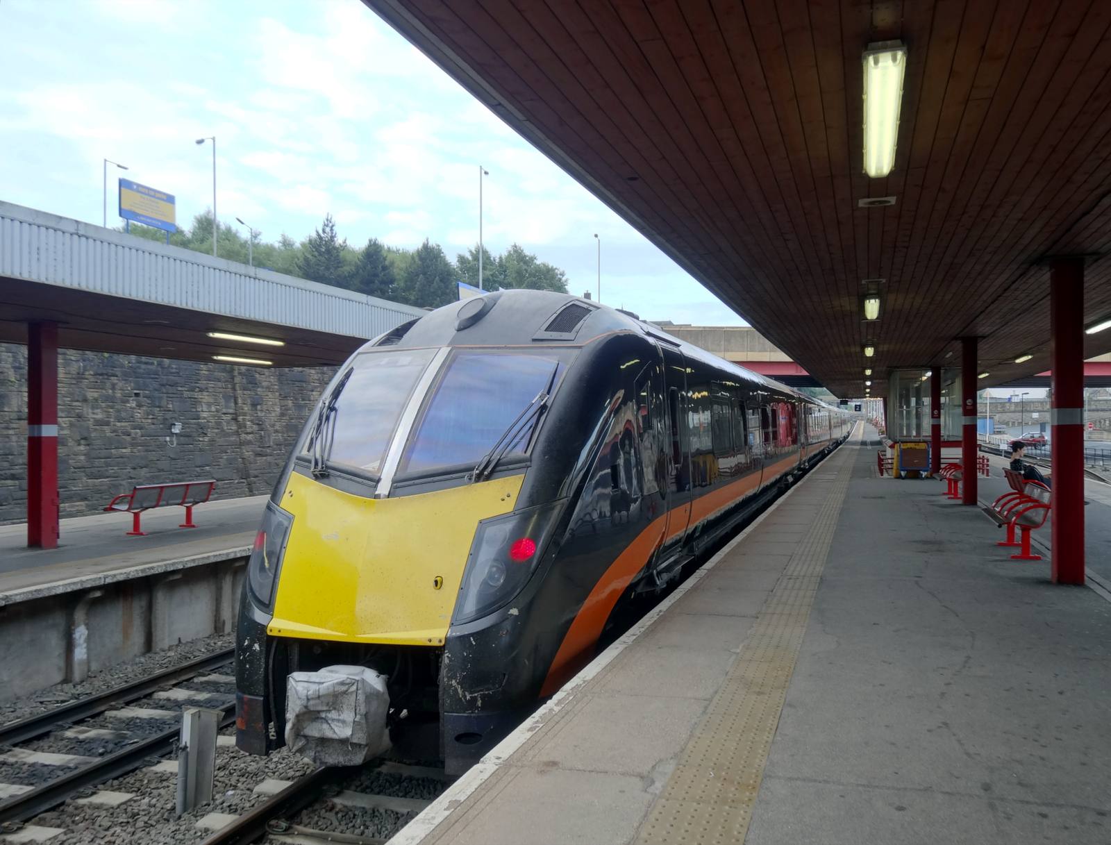 A Grand Central train with a yellow front standing at a platform under the canopy at Bradford Interchange