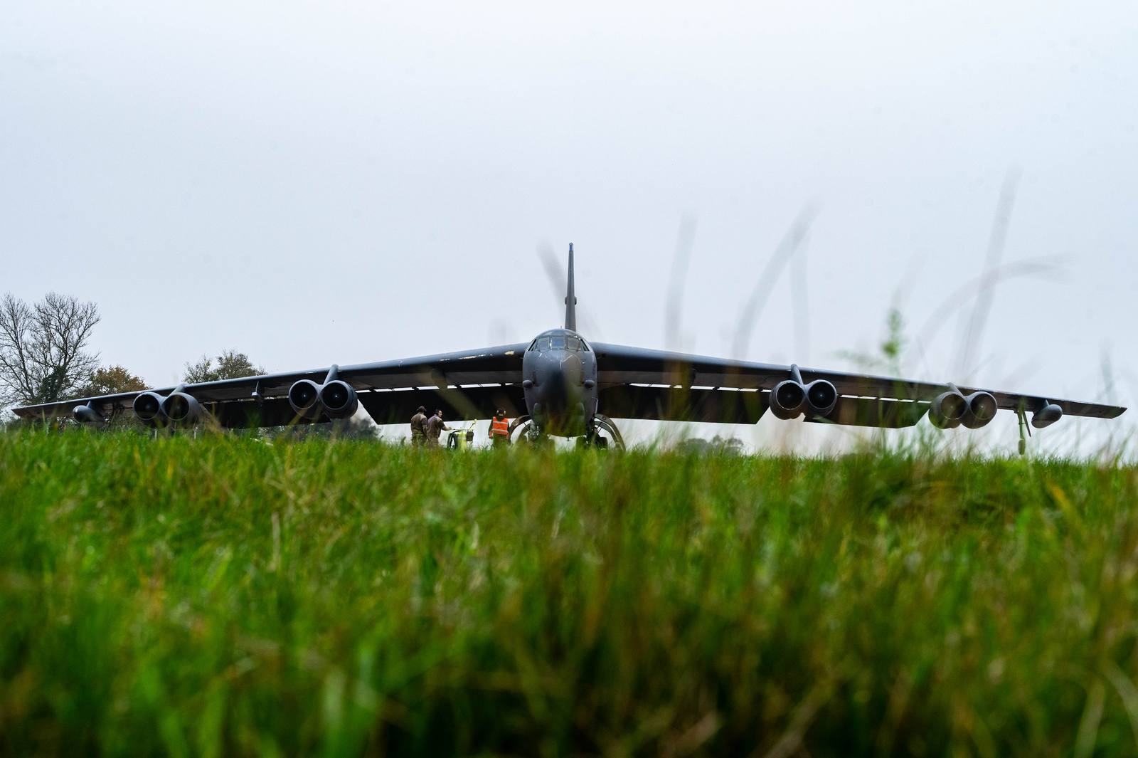 A B-52H Stratofortress seen head-on at RAF Fairford with airmen underneath its wing