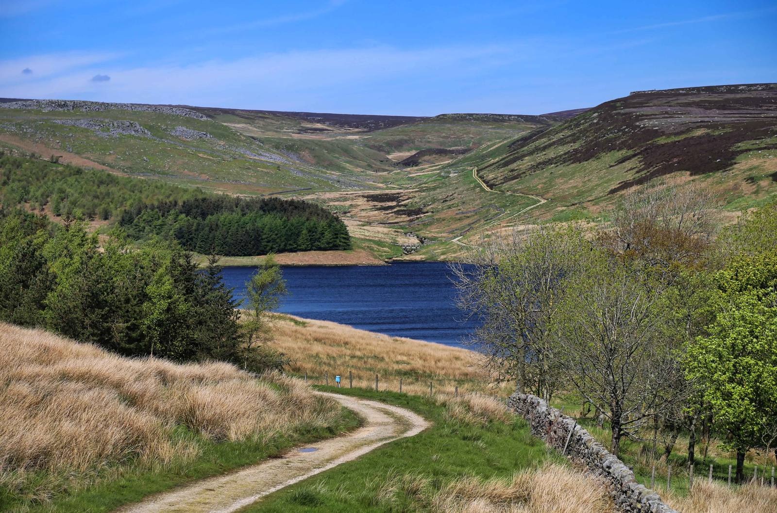 Grimwith Reservoir in North Yorkshire, with moorland hills, a stone wall and a path in the foreground