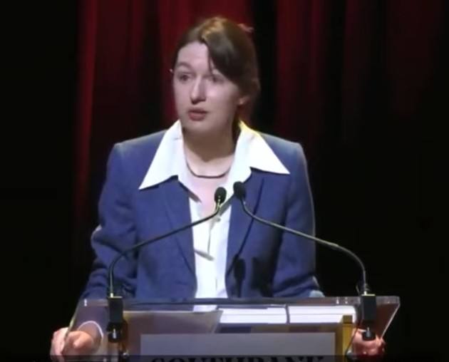 Sally Rooney speaking at a lectern with two microphones
