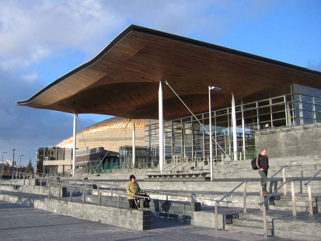 The wooden canopy of the Senedd in Cardiff Bay, with the Wales Millennium Centre visible behind it