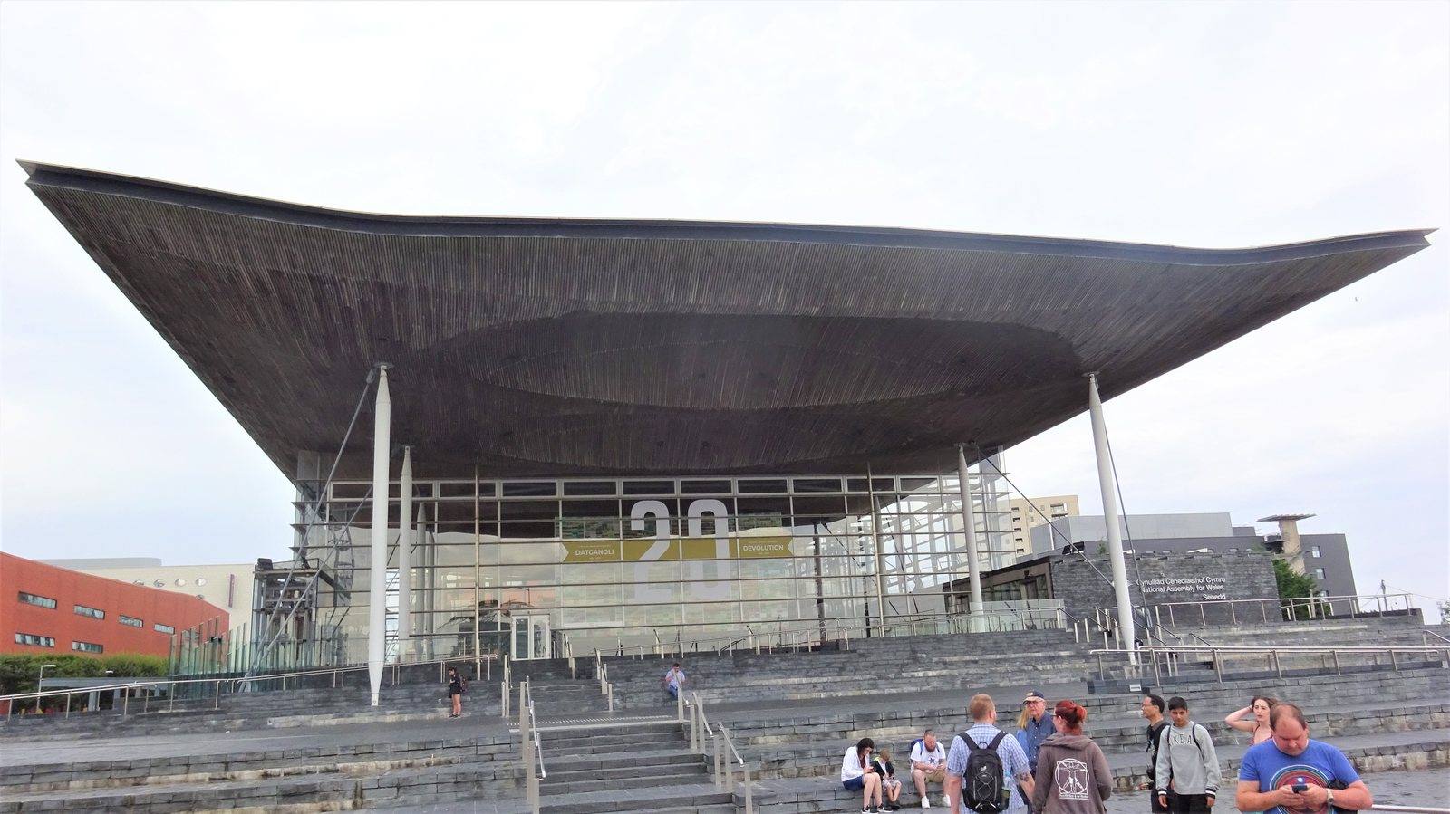 The glass frontage and sweeping roof of the Senedd building in Cardiff Bay, seen from the steps