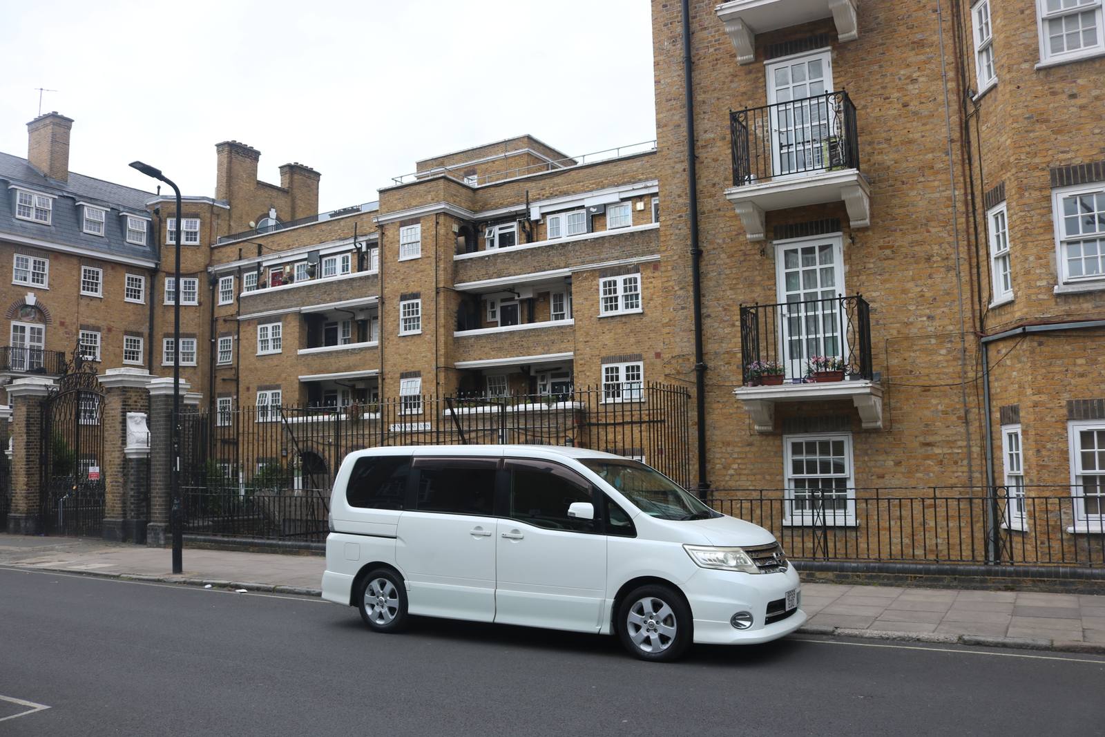 Yellow brick council flats with balconies on Werrington Street in Somers Town, with a white van parked in the foreground