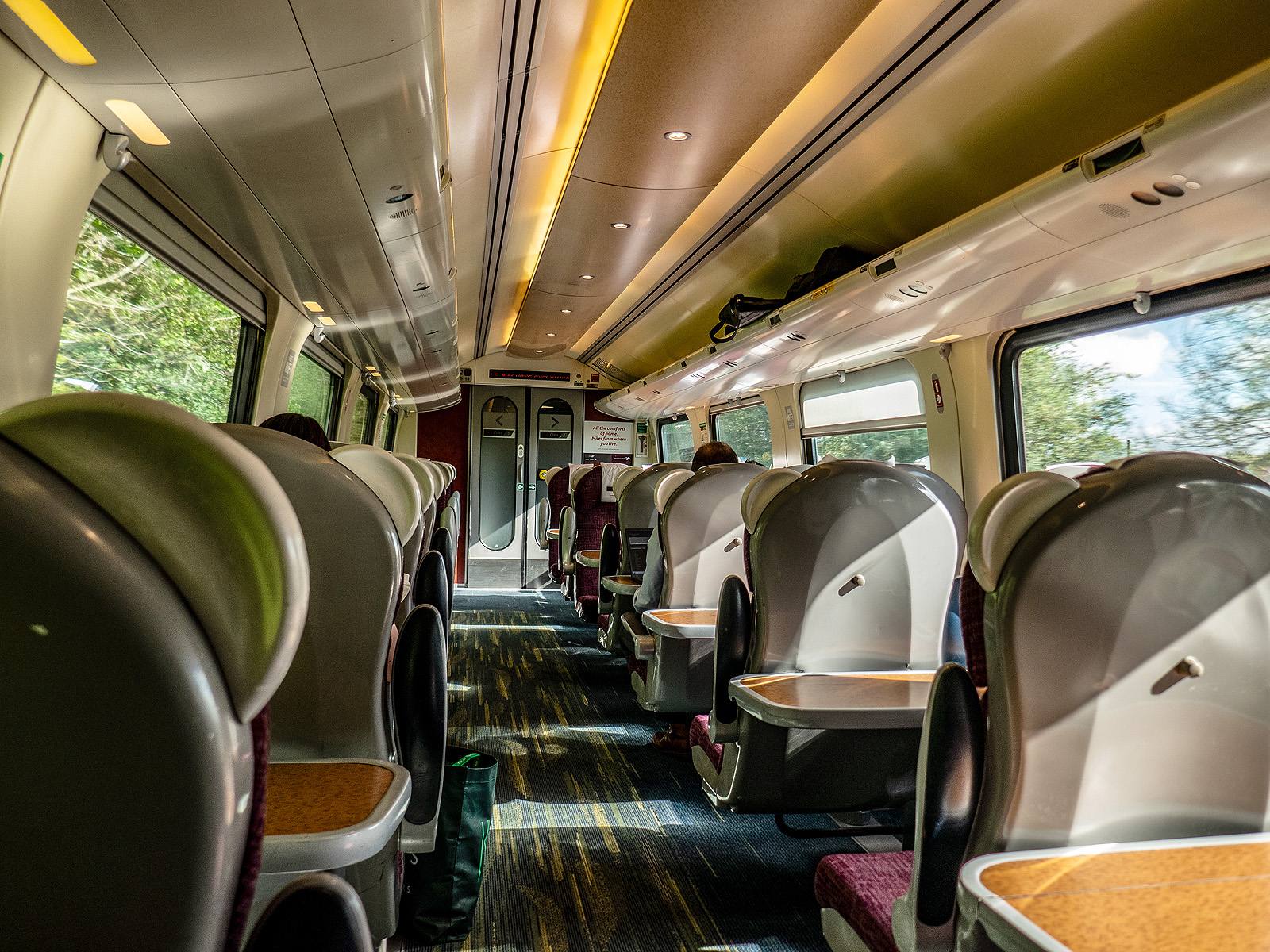 The interior of a CrossCountry train carriage, with rows of seats, tables and passengers seen from behind