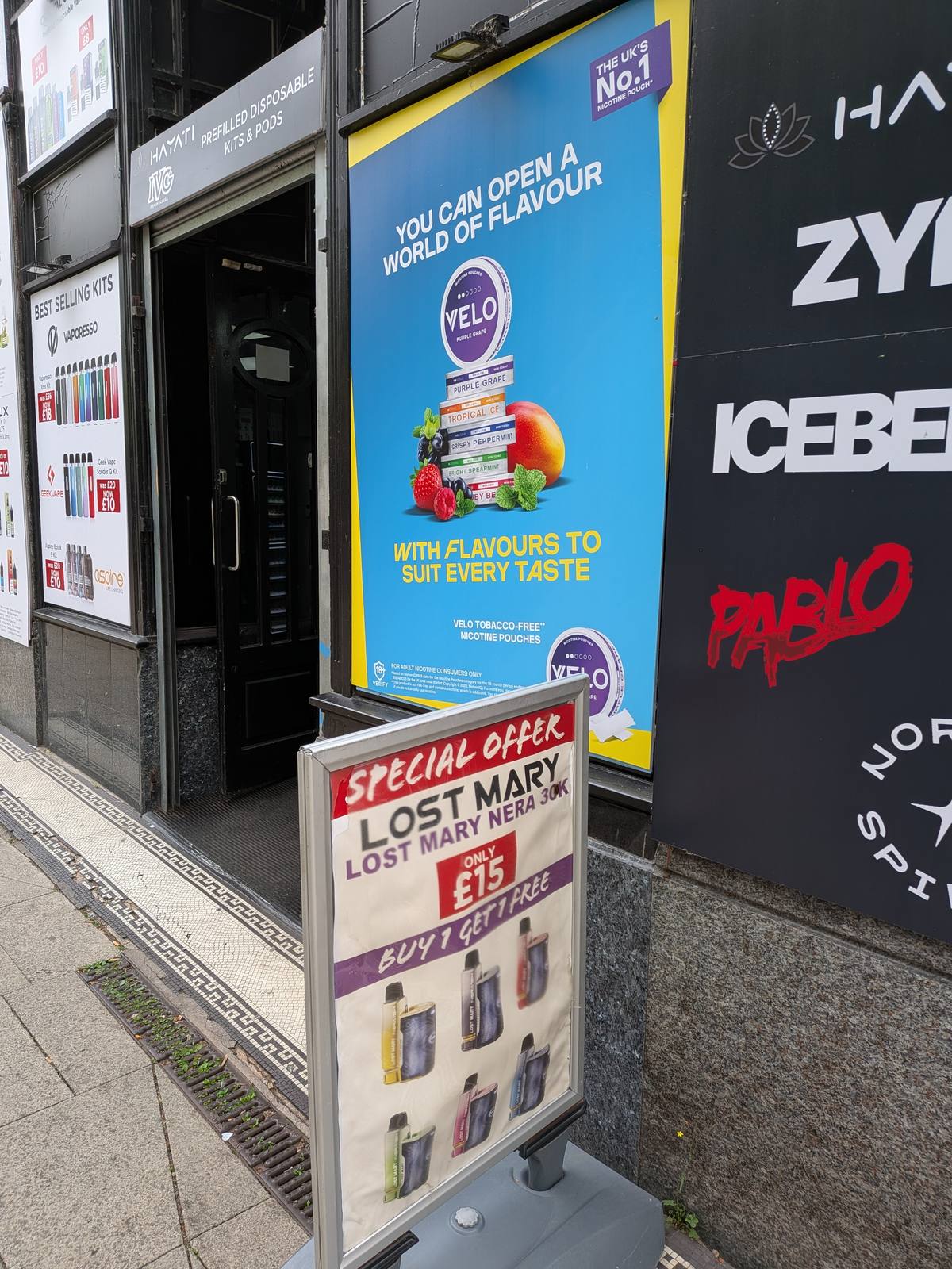 A vape shop storefront in Manchester with vaping product advertisements
